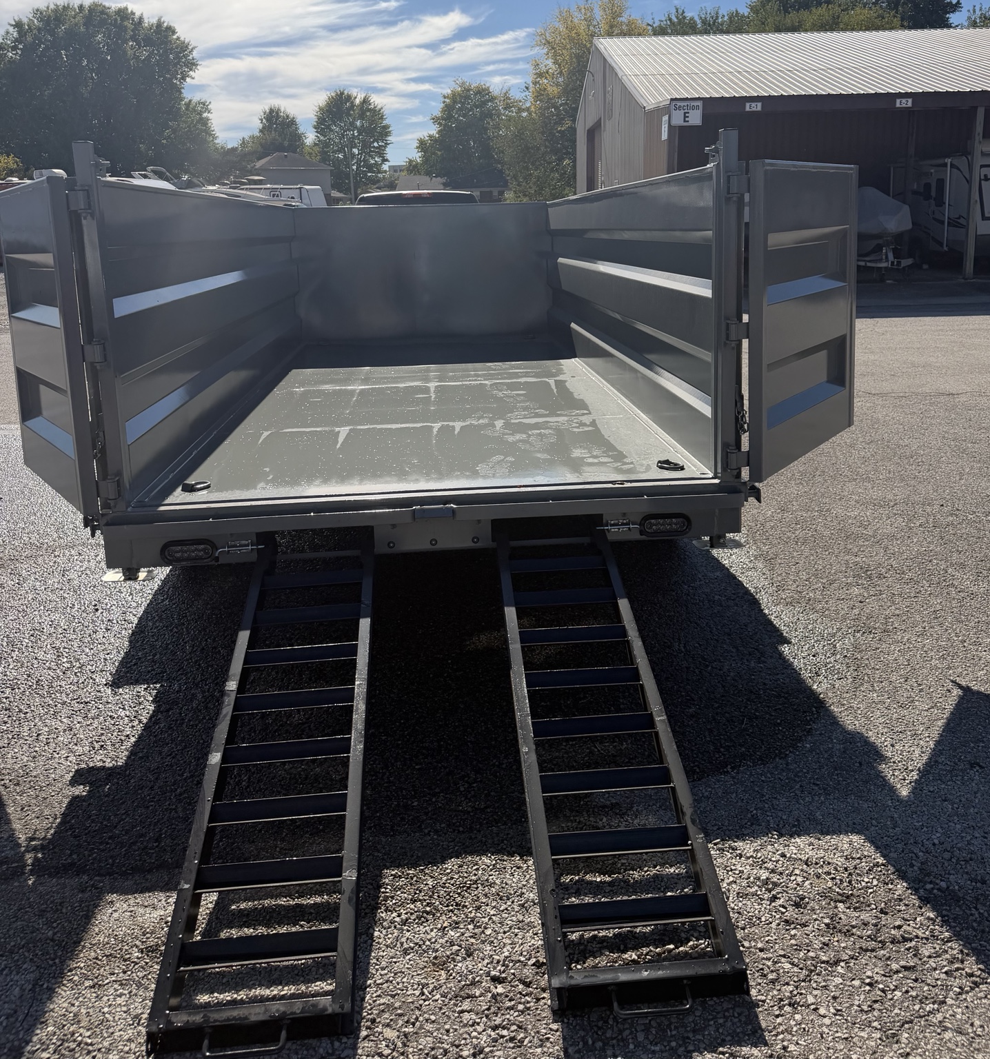 K40 dump trailer with rear doors open and loading ramps extended